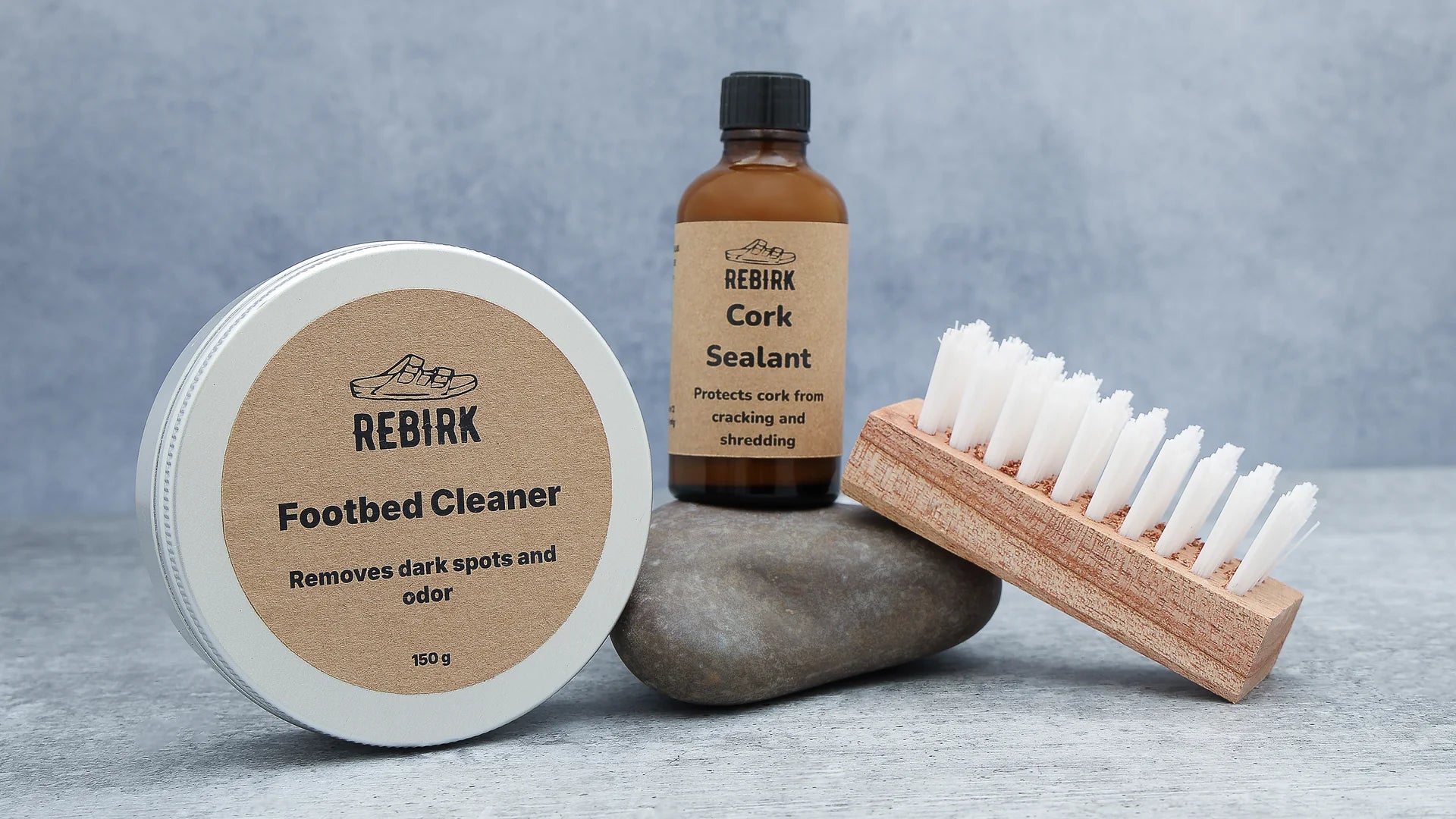 Footbed cleaner, cork sealant, and brush on a gray surface with a gray background